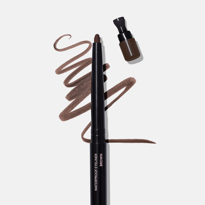 Uncapped Mary Kay Waterproof Eyeliner in Brown against product rub next to sharpener cap