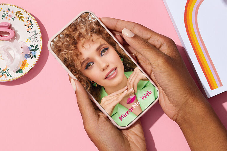 Hand holding a phone showing  Mary Kay MirrorMe web virtual try on