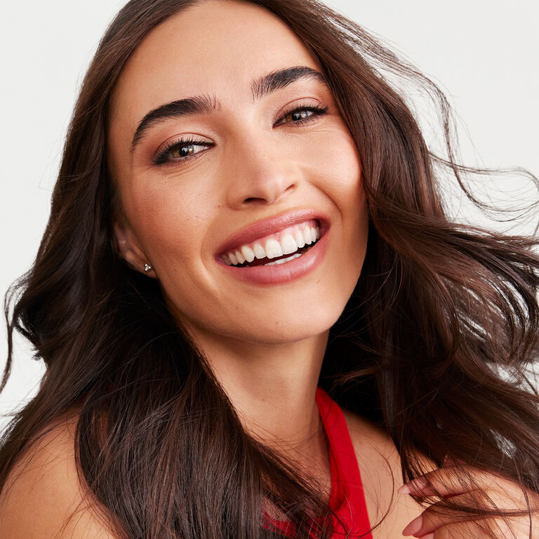 A brunette model wearing the Saharan Dusk look appears smiling.